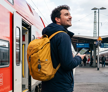 Ein Reisender am Bahngleis vor einfahrendem Zug